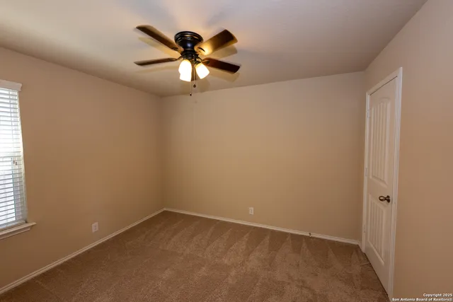 an empty room with a window and a fan