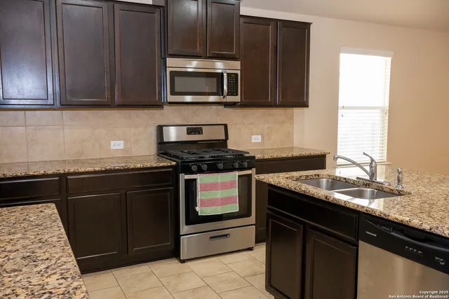 a kitchen with granite countertop cabinets stainless steel appliances and a sink