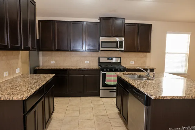 a kitchen with stainless steel appliances granite countertop a stove sink and microwave