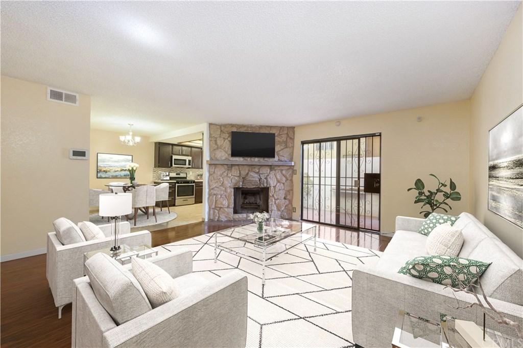 Spacious living room has open concept to dining area and kitchen. Charming fireplace and sliders lead to outside. *Photo is virtually staged.