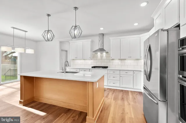 a kitchen with white cabinets stainless steel appliances and a chandelier