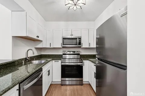 a kitchen with granite countertop a stove sink and cabinets