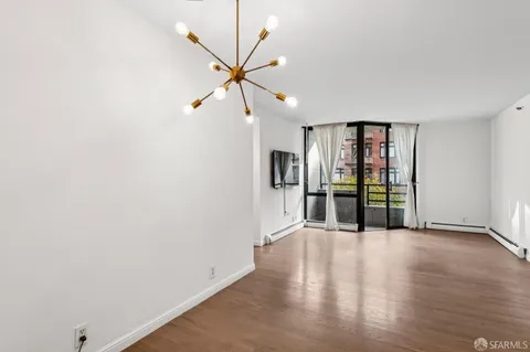 a view of an empty room with window and wooden floor