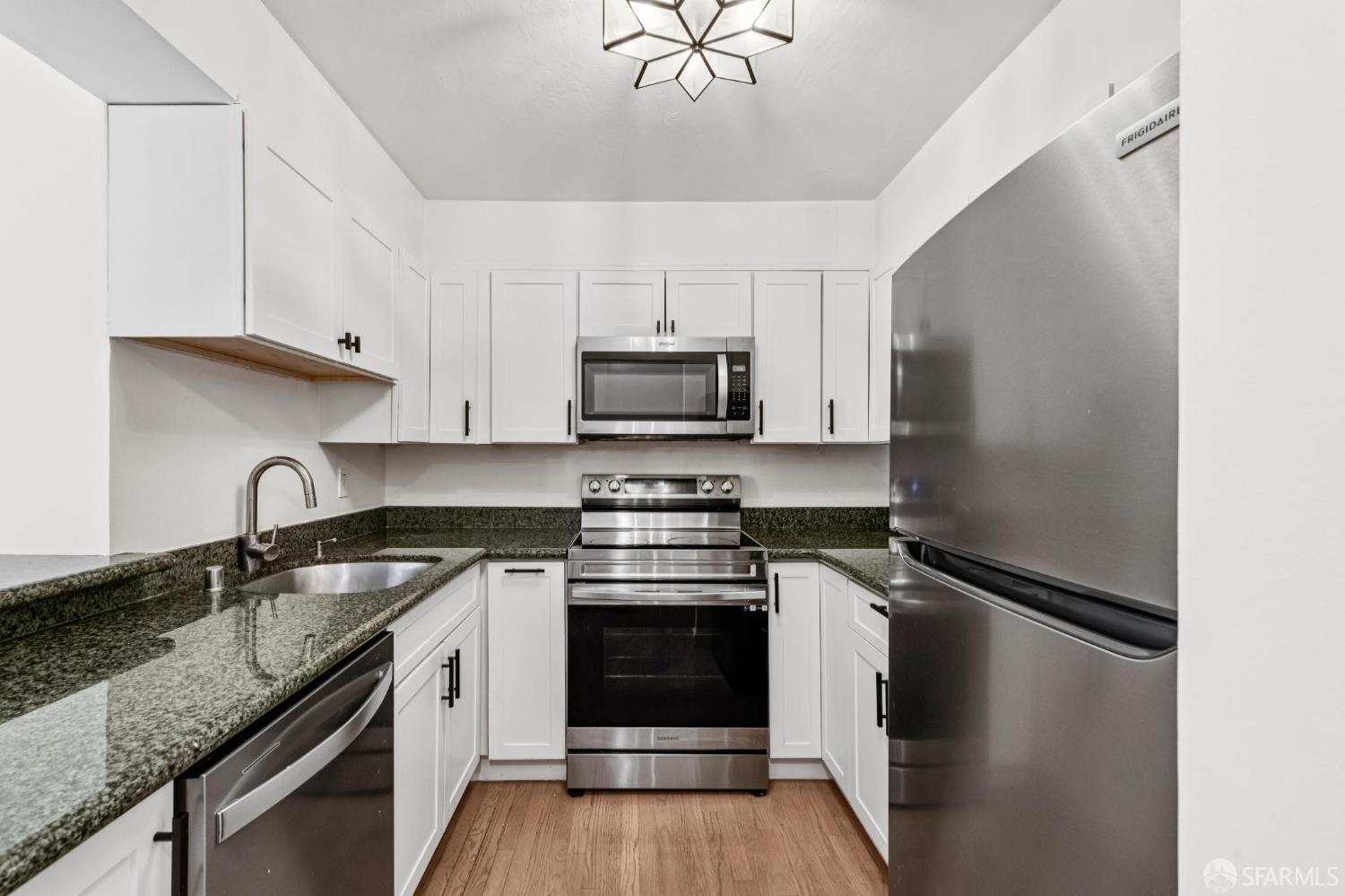 900 Bush Street, Unit 309 San Francisco, CA 94109 - Photo 9 of 25 a kitchen with granite countertop a stove sink and cabinets