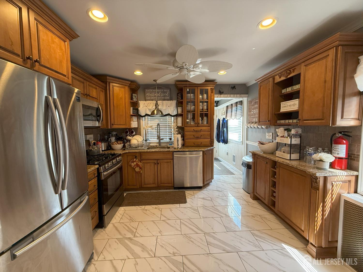 a kitchen with stainless steel appliances granite countertop a refrigerator a stove top oven a sink dishwasher and white cabinets with wooden floor