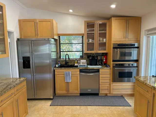 a kitchen with stainless steel appliances granite countertop sink stove refrigerator and cabinets