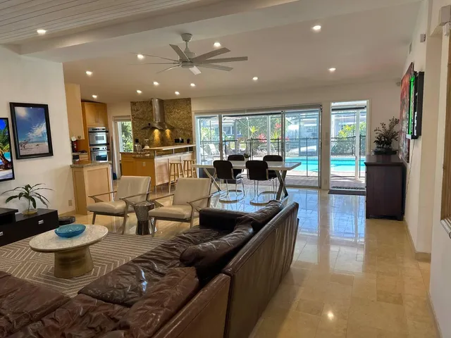 a living room with furniture kitchen view and a large window