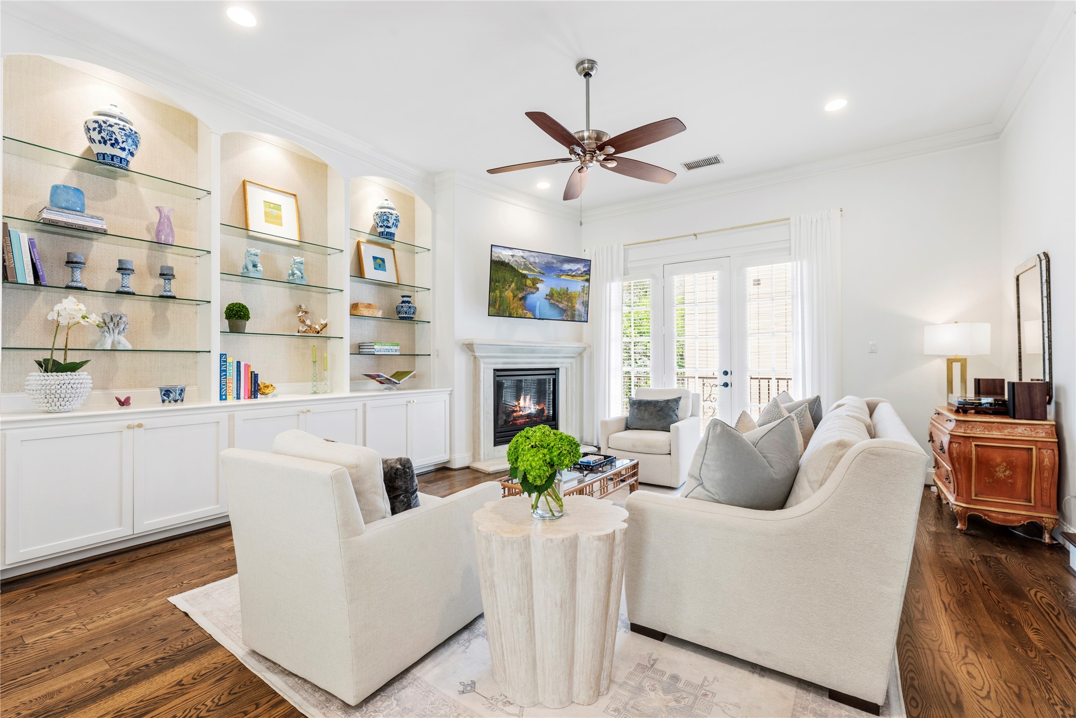 1537 Haddon Street Houston, TX 77006 - Photo 11 of 48 Bright and spacious living room with elegant hardwood floors, built-in shelving, and a cozy fireplace. Features a ceiling fan, comfortable seating, and French doors leading to a balcony. Ideal for relaxation and entertaining.