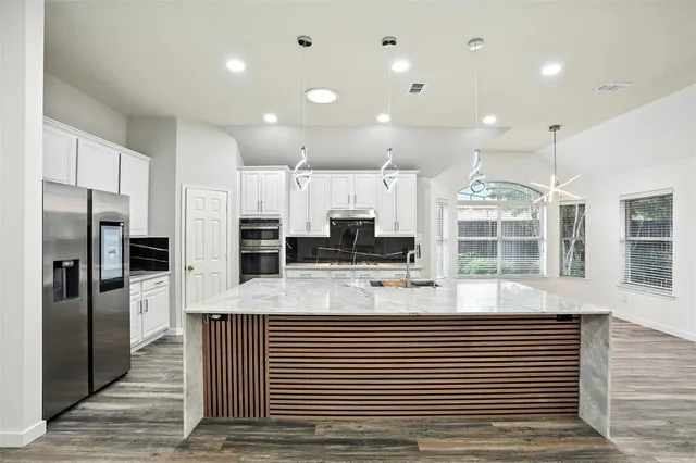 a large kitchen with stainless steel appliances kitchen island a large counter top a stove and a refrigerator