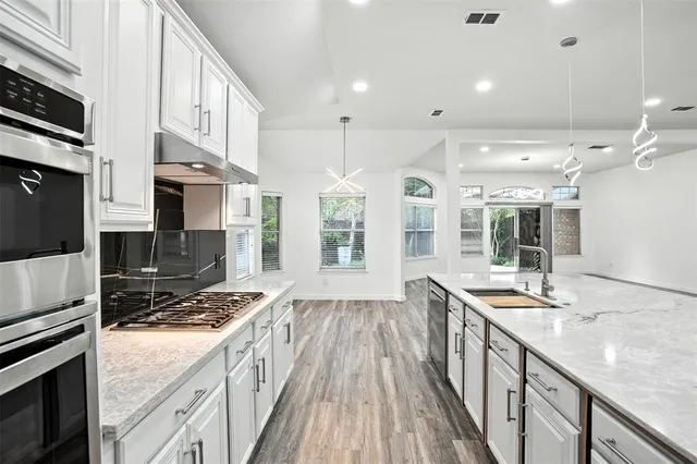 a kitchen with stainless steel appliances kitchen island granite countertop a stove and a sink