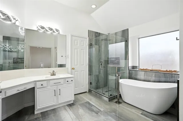 a bathroom with a large tub a double vanity sink a mirror and a shower