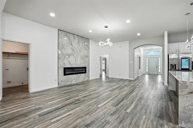 a view of an empty room with wooden floor and a kitchen