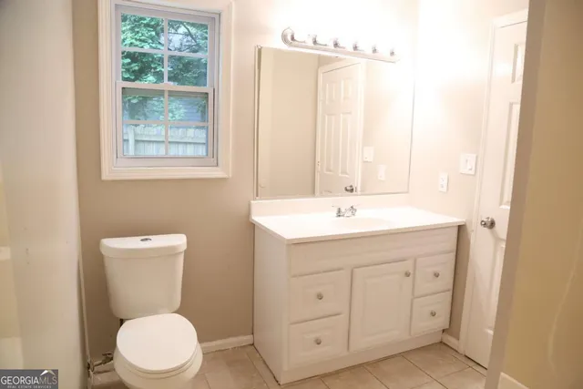 a bathroom with a toilet a sink a mirror a window and vanity