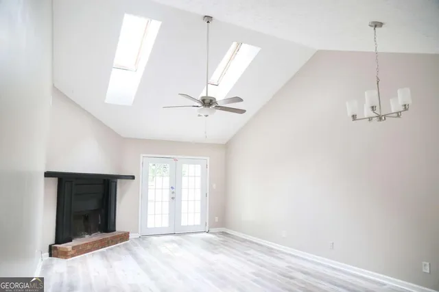 a view of an empty room with window and chandelier fan
