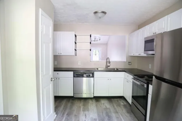a kitchen with stainless steel appliances a sink and wooden floor