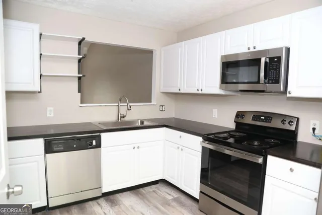 a kitchen with white cabinets and appliances