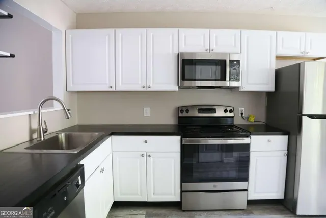 a kitchen with granite countertop white cabinets and stainless steel appliances