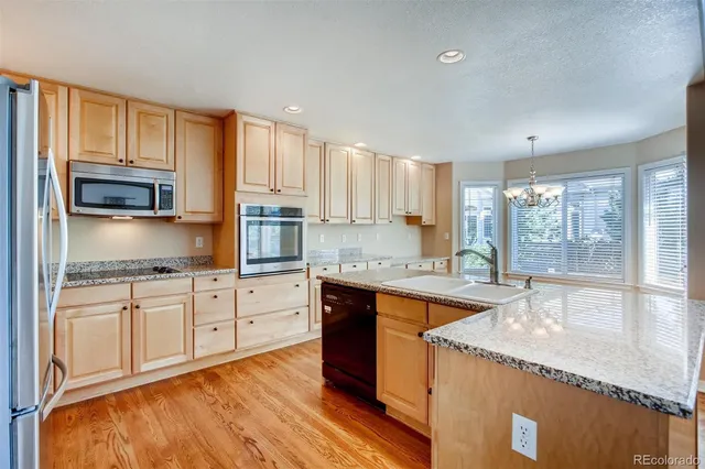 a kitchen with stainless steel appliances granite countertop a stove a sink and a refrigerator