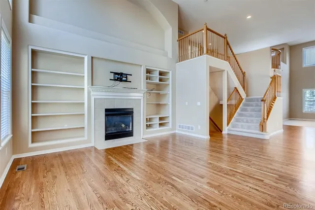 a view of an empty room with wooden floor fireplace and a window
