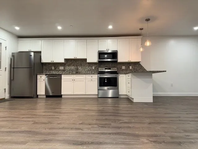 a kitchen with stainless steel appliances granite countertop a stove a sink and a refrigerator