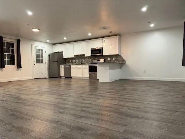 a kitchen with stainless steel appliances wooden floor and refrigerator