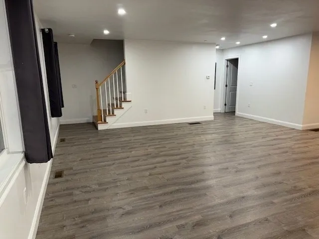 an empty room with wooden floor and stairs