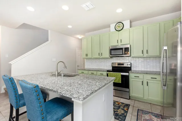 a kitchen with kitchen island granite countertop a table chairs microwave and sink