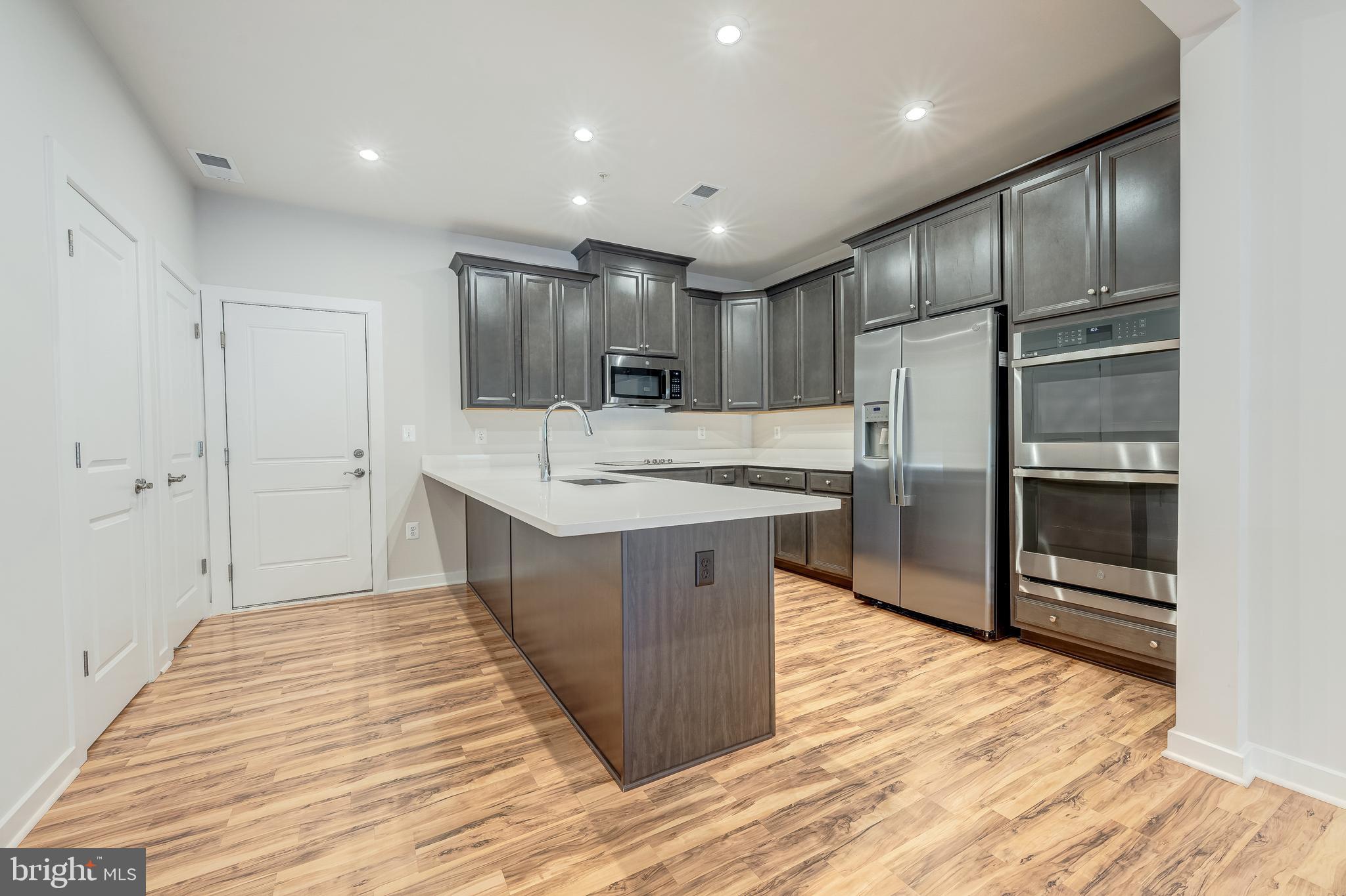 13504 Innovation Station Loop, Unit 2A Herndon, VA 20171 - Photo 14 of 36 a large kitchen with kitchen island a sink stainless steel appliances and cabinets