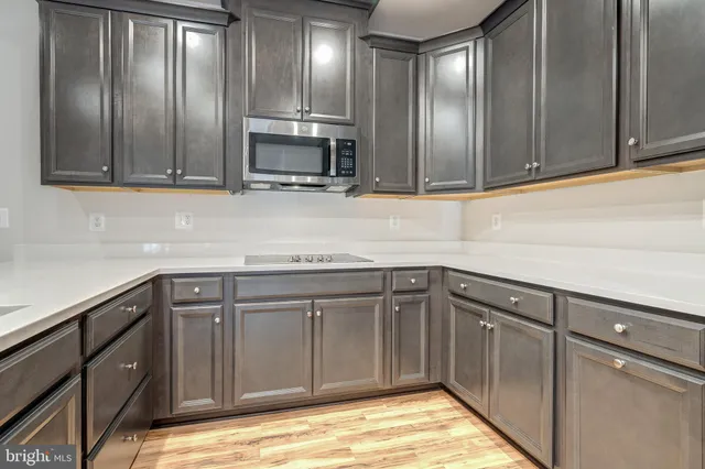 a kitchen with stainless steel appliances granite countertop a sink and cabinets with wooden floor