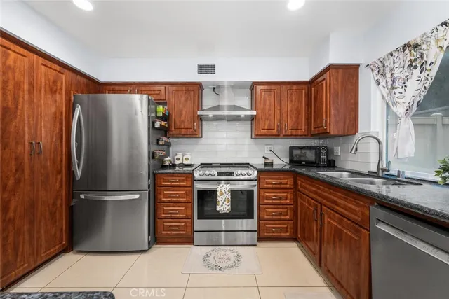 a kitchen with stainless steel appliances granite countertop a stove top oven a refrigerator and a cabinets