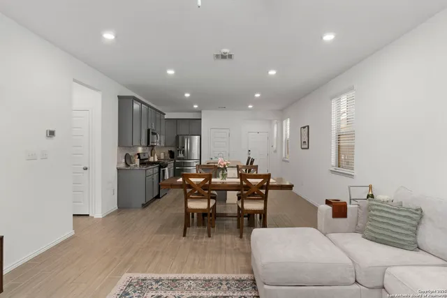a living room with furniture and a dining table with wooden floor