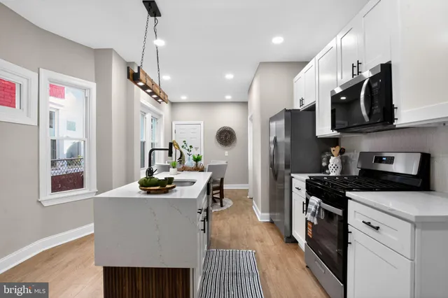 a kitchen with stainless steel appliances kitchen island granite countertop a refrigerator a sink dishwasher a stove and a dining table with wooden floor