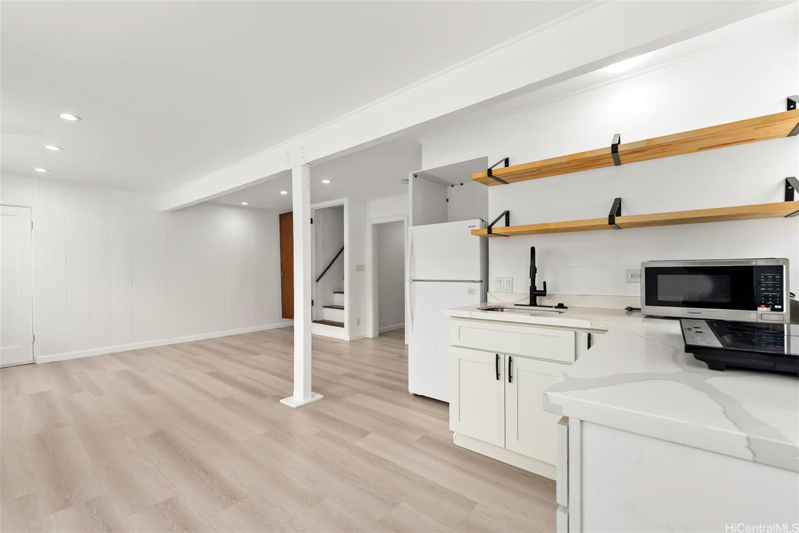 2811 Henry Street Honolulu, HI 96817 - Photo 16 of 25 The charming lower-level kitchenette boasts crisp white cabinetry, striking black hardware, and beautiful open wood shelving for a modern touch.