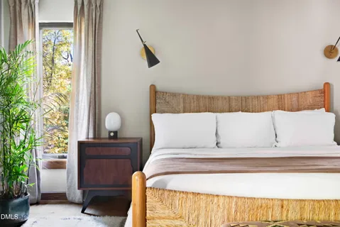 a bed sitting in a bedroom next to a window with potted plants