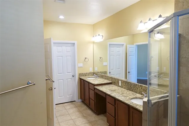a bathroom with a granite countertop sink a mirror and a shower
