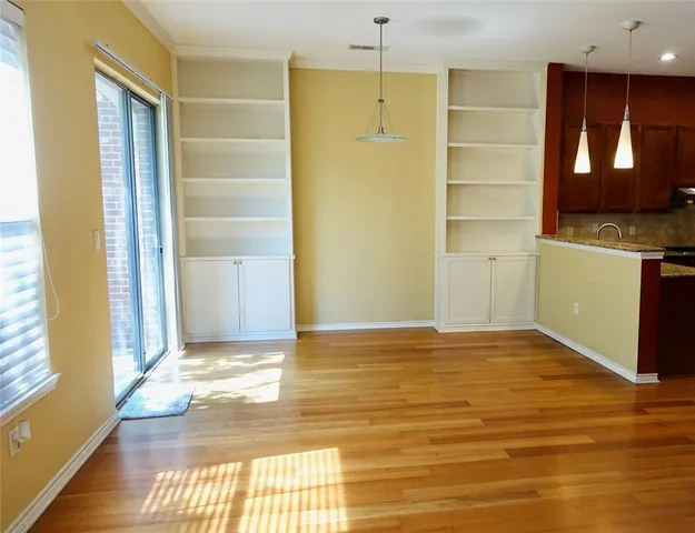 a view of an empty room with window and wooden floor