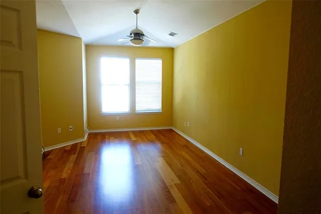 a view of an empty room with wooden floor and a window