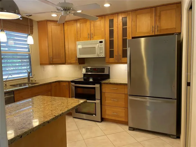 a kitchen with stainless steel appliances granite countertop a refrigerator a stove and a sink