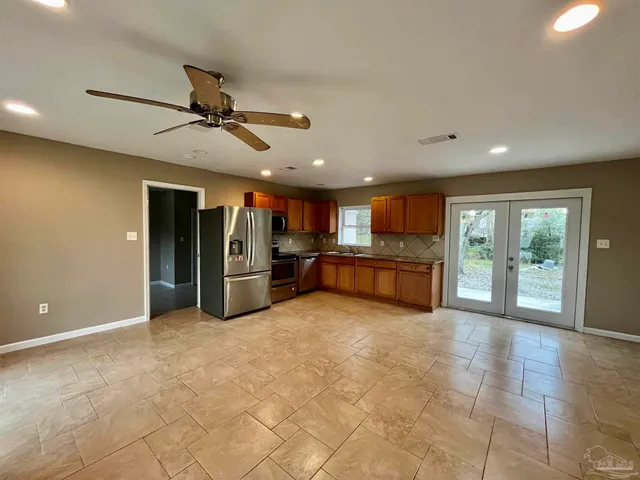 a large kitchen with stainless steel appliances kitchen island granite countertop a refrigerator and a sink