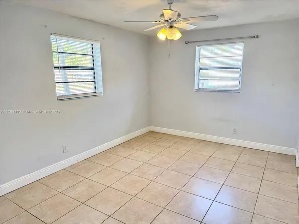 an empty room with windows and chandelier fan