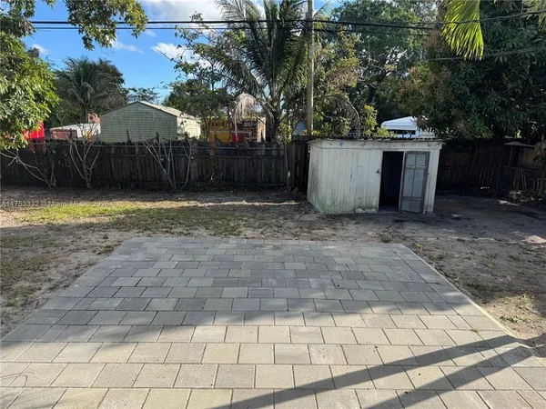 a view of a backyard with large trees and wooden fence