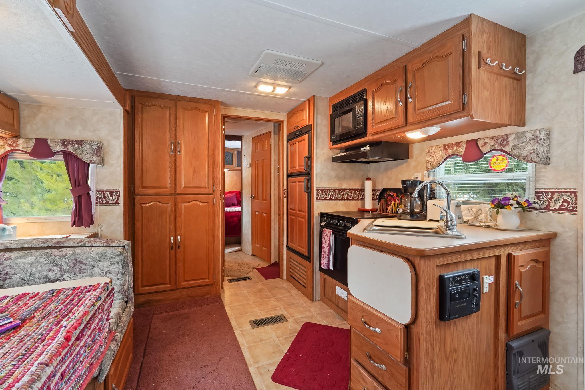 881 West Roseberry Road Donnelly, ID 83615 - Photo 22 of 24 Kitchen featuring wood finish cabinetry, healthy amount of natural light, black appliances, and range hood