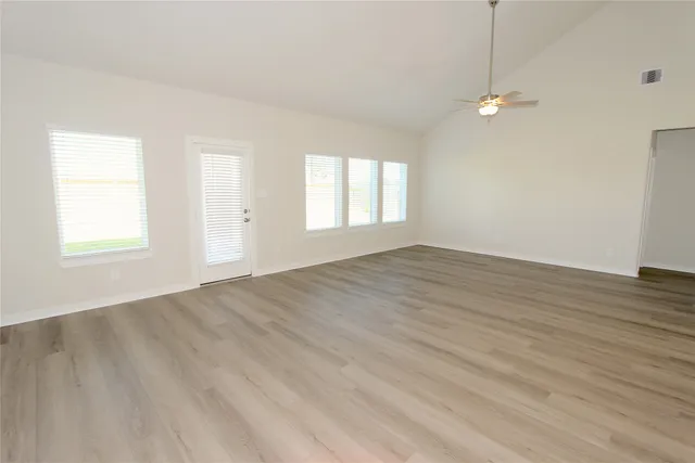an empty room with wooden floor and windows