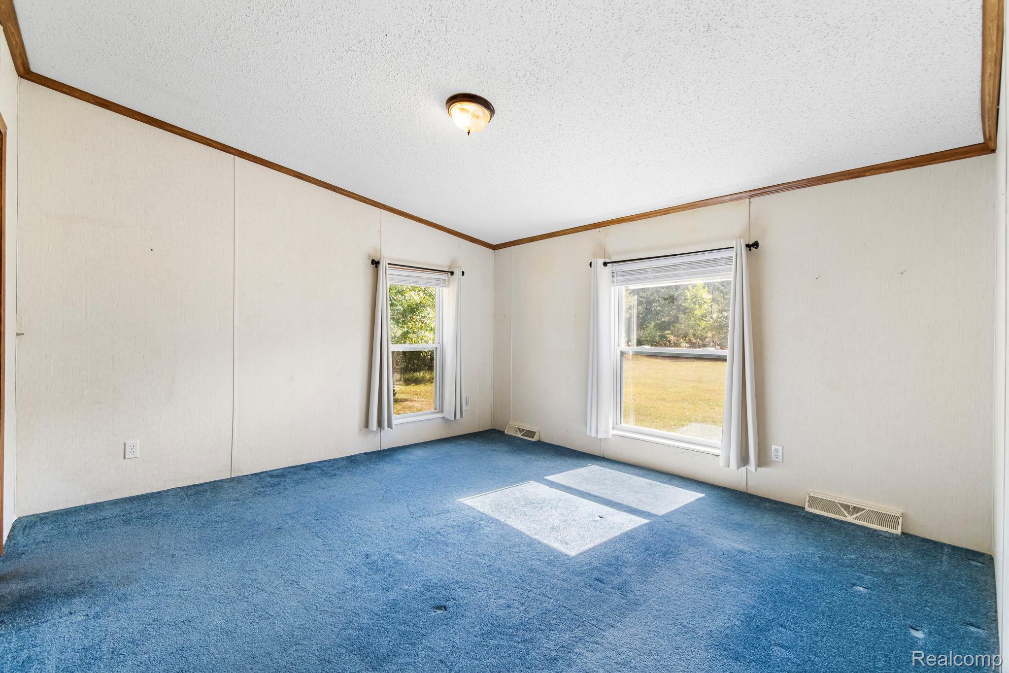 4884 Griffin Road Lewiston, MI 49756 - Photo 16 of 41 Room featuring two windows, carpeted flooring, and a ceiling-mounted light fixture