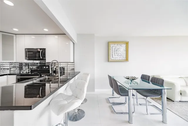 a kitchen with stainless steel appliances kitchen island granite countertop a stove a sink a dining table and chairs