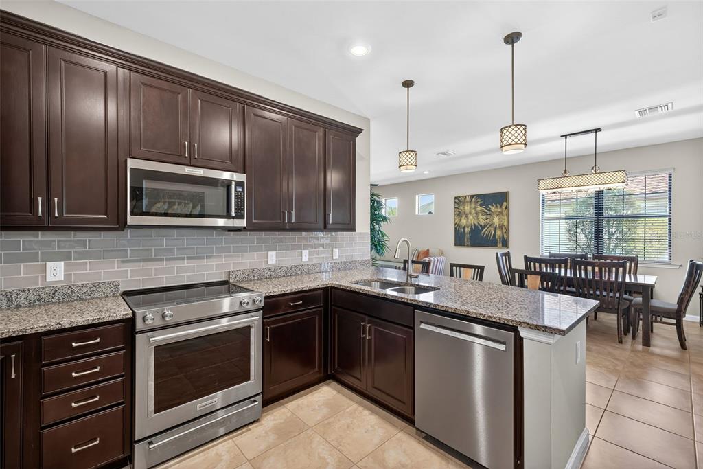 5821 Mayflower Way Ave Maria, FL 34142 - Photo 12 of 36 a kitchen with stainless steel appliances granite countertop a sink stove and microwave