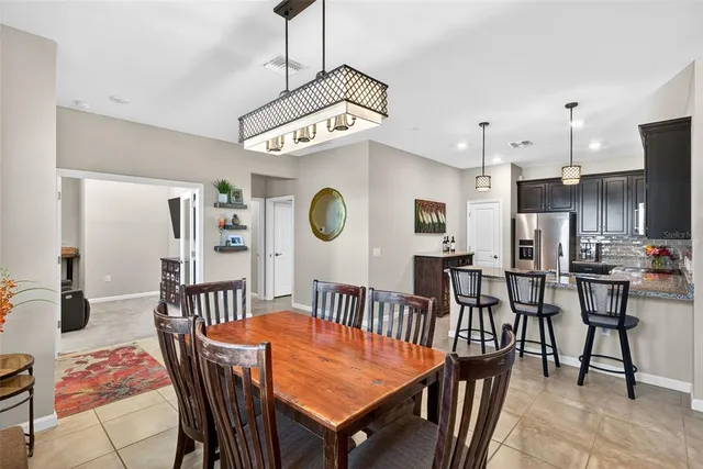a view of a dining room and livingroom with furniture wooden floor a rug a painting and a chandelier