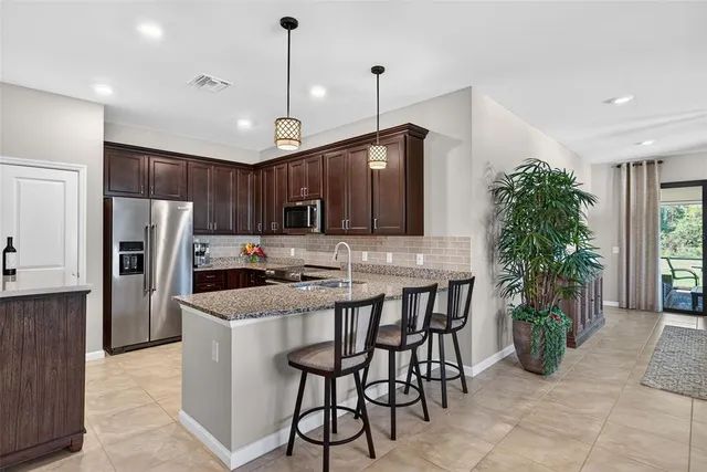 a kitchen with stainless steel appliances kitchen island granite countertop a refrigerator a stove a sink and a oven