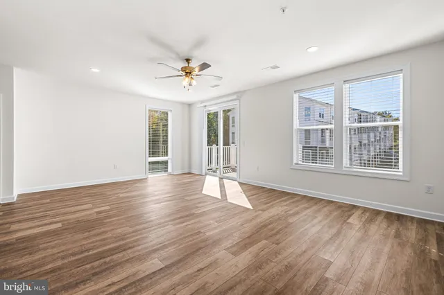 a view of an empty room with a window and wooden floor