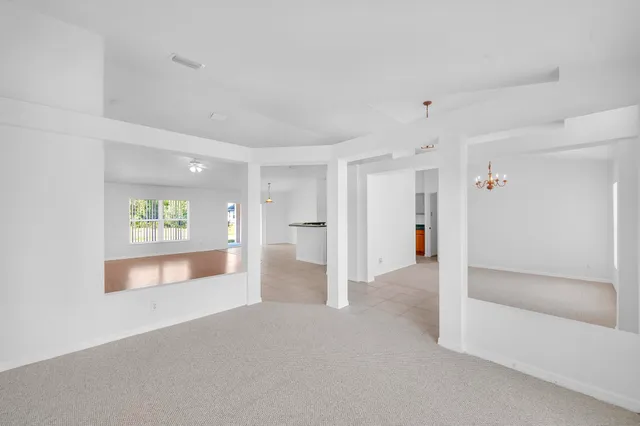 a view of an empty room and a kitchen